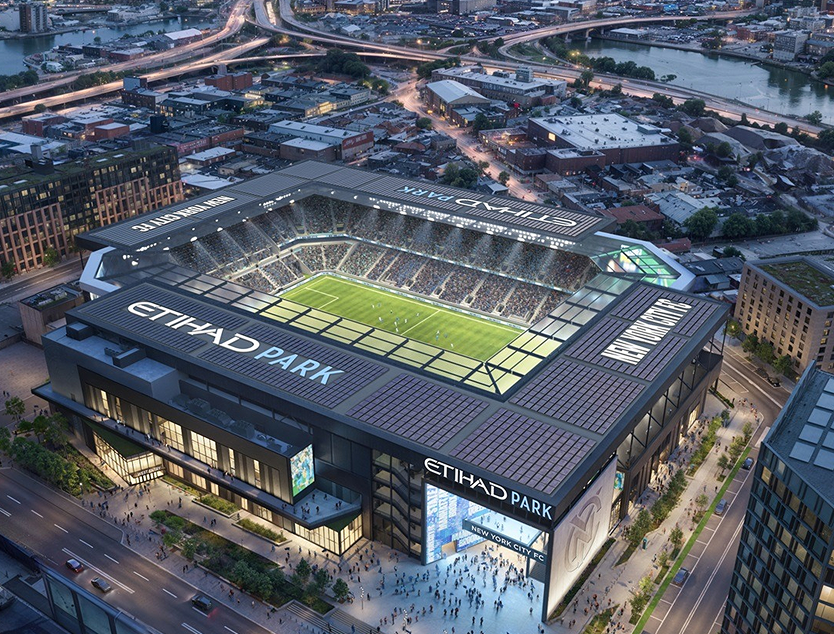 Render aéreo de Etihad Park con la cancha iluminada dentro del estadio.